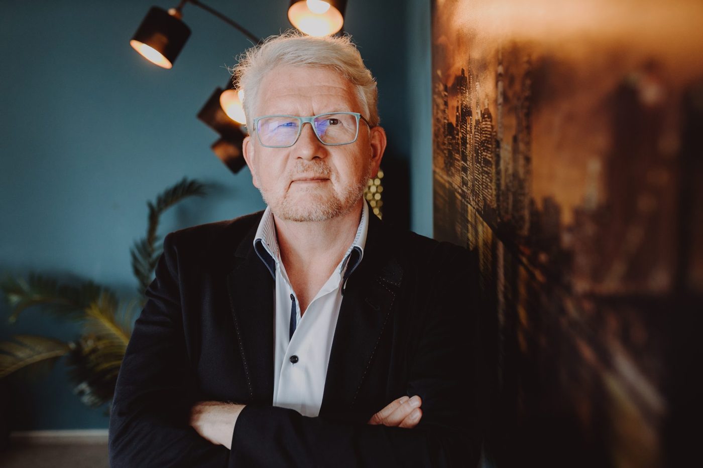 Detlef Gumze sitzt am Tisch, warmes Licht, petrolfarbene Wand